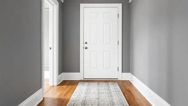 Freshly painted white trim and paneled door in a bright front hallway