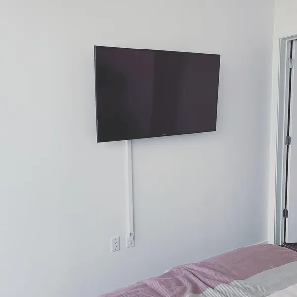 Bedroom TV wall mount installation with a clean white cord raceway
