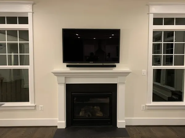 TV and soundbar mounted perfectly centered above a fireplace mantel